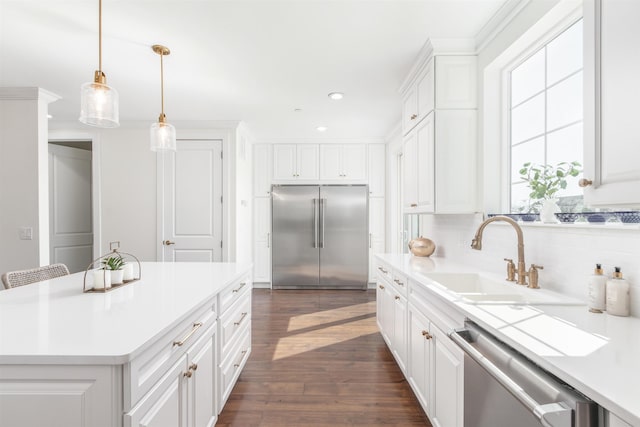 kitchen with sink, appliances with stainless steel finishes, white cabinetry, hanging light fixtures, and a center island