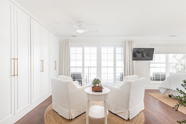 living area featuring dark wood-type flooring, ceiling fan, and ornamental molding