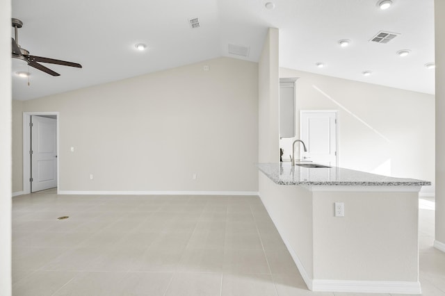 kitchen featuring kitchen peninsula, lofted ceiling, sink, ceiling fan, and light stone counters