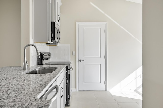 kitchen with tasteful backsplash, sink, white cabinets, light stone counters, and stainless steel appliances