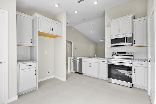 kitchen with white cabinetry, lofted ceiling, sink, stainless steel appliances, and light stone countertops