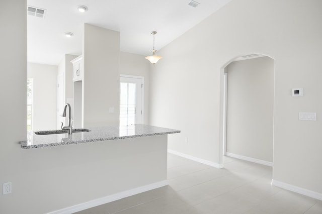 kitchen featuring sink, white cabinetry, decorative light fixtures, kitchen peninsula, and light stone countertops