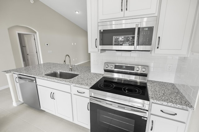 kitchen featuring stainless steel appliances, white cabinetry, light stone countertops, and sink