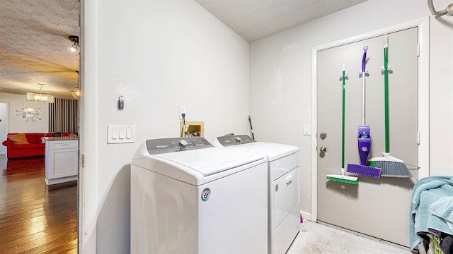 clothes washing area featuring laundry area, wood-type flooring, separate washer and dryer, and a textured ceiling