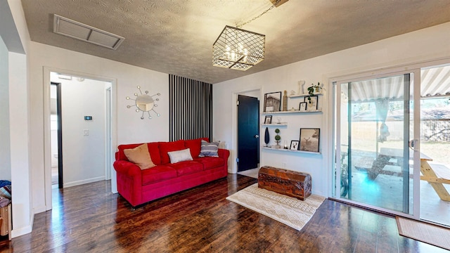 living area with baseboards, a textured ceiling, visible vents, and wood finished floors