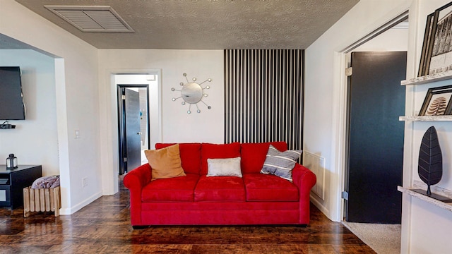 living room with visible vents, a textured ceiling, baseboards, and wood finished floors