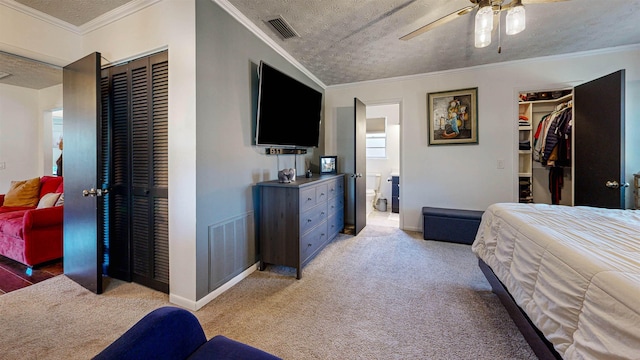 carpeted bedroom featuring a closet, visible vents, crown molding, and a textured ceiling