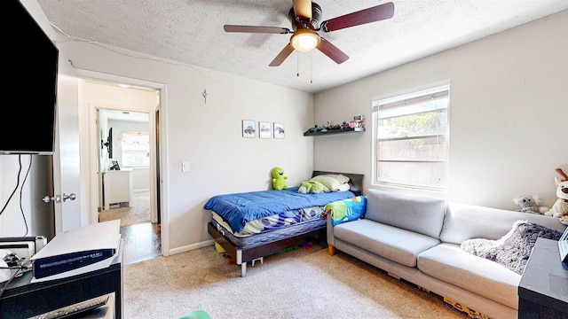 carpeted bedroom featuring baseboards, a ceiling fan, and a textured ceiling