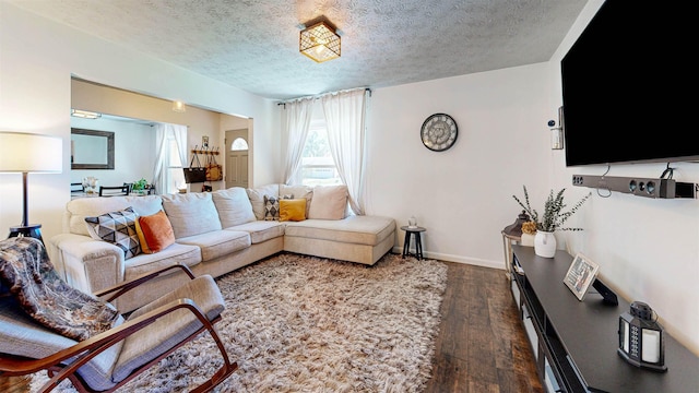 living room with dark wood-type flooring, a textured ceiling, and baseboards