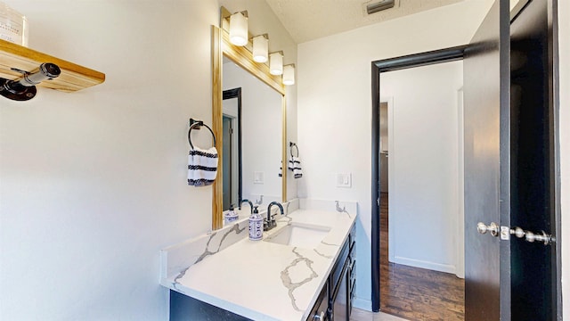 bathroom with visible vents, vanity, baseboards, and wood finished floors