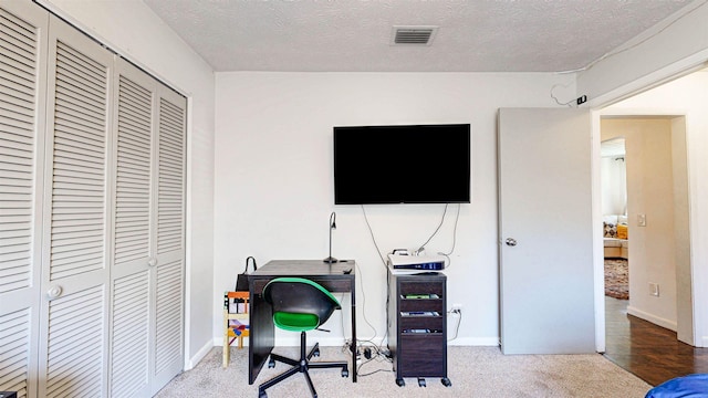 office area featuring carpet floors, visible vents, a textured ceiling, and baseboards