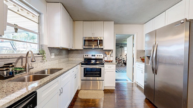 kitchen featuring stainless steel appliances, dark wood-style flooring, white cabinetry, and a sink