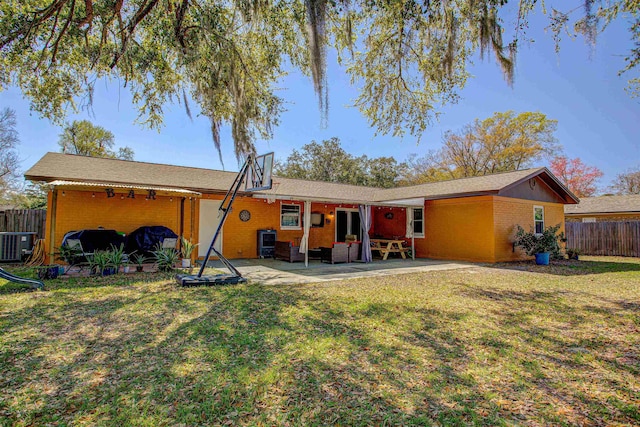 back of property featuring a yard, a patio area, fence, and brick siding