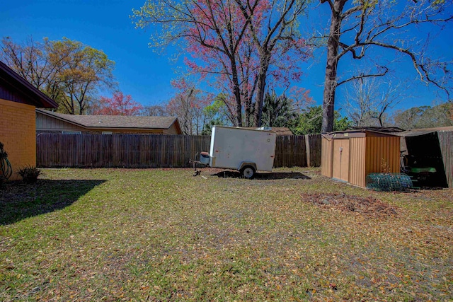 view of yard featuring a fenced backyard, an outdoor structure, and a storage unit