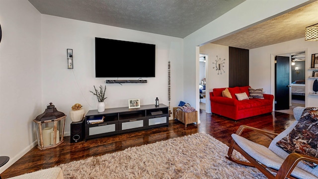 living room with a textured ceiling, hardwood / wood-style floors, and baseboards