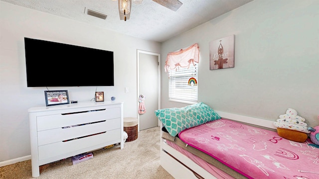 bedroom with a textured ceiling, a ceiling fan, visible vents, and light colored carpet