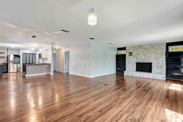 132 Southwind Cir, Saint Augustine, FL 32080 - unfurnished living room featuring dark wood-style flooring, a stone fireplace, and a chandelier