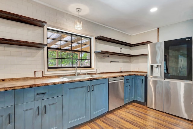 132 Southwind Cir, Saint Augustine, FL 32080 - kitchen with open shelves, stainless steel appliances, blue cabinetry, wood counters, and backsplash