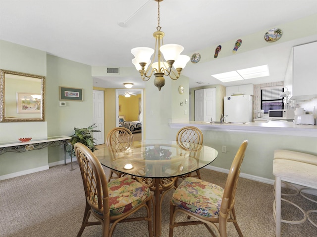 4250 A1A S L25, Saint Augustine, FL 32080 - dining space with a chandelier, light colored carpet, a skylight, and baseboards
