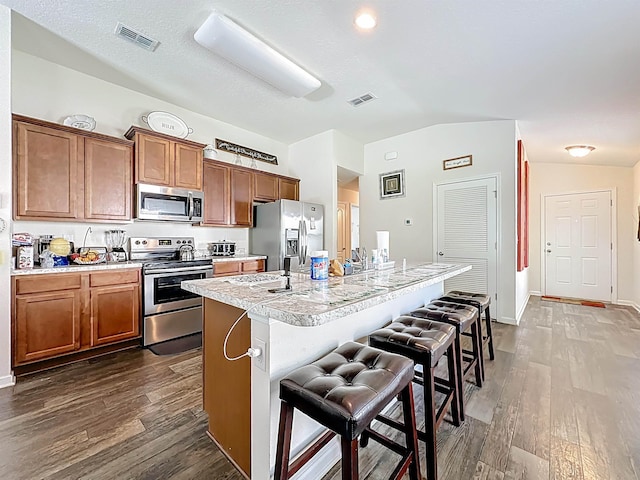 348 Ashby Landing Way, Saint Augustine, FL 32086 - kitchen with stainless steel appliances, brown cabinetry, dark wood-type flooring, light countertops, and lofted ceiling