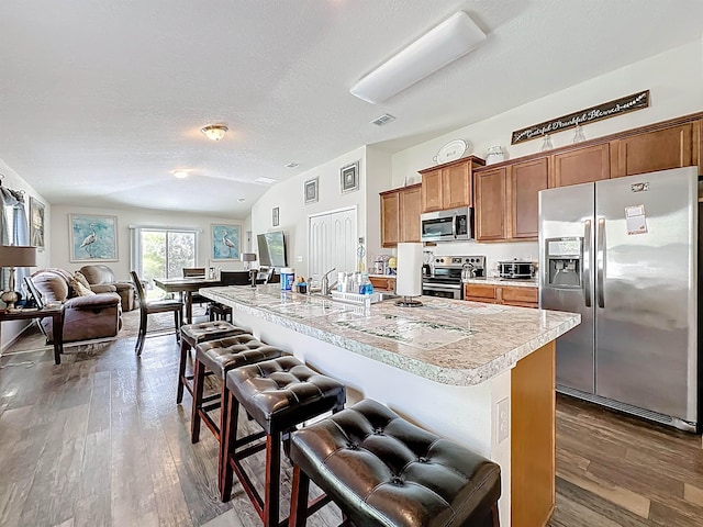 348 Ashby Landing Way, Saint Augustine, FL 32086 - kitchen featuring appliances with stainless steel finishes, light countertops, brown cabinetry, a breakfast bar area, and wood finished floors