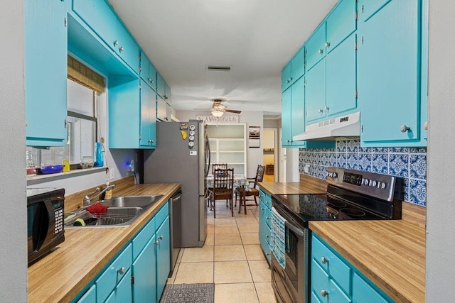 kitchen featuring stainless steel appliances, under cabinet range hood, a sink, decorative backsplash, and blue cabinetry