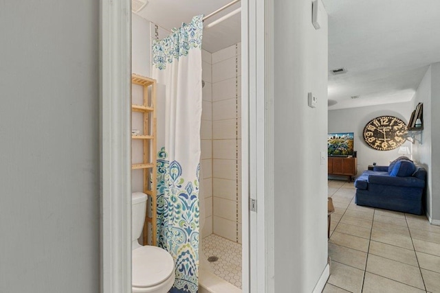 ensuite bathroom featuring a shower stall, tile patterned flooring, toilet, and baseboards