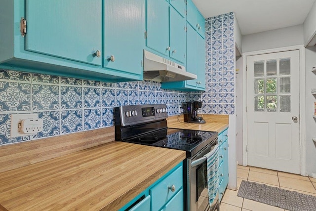 kitchen with under cabinet range hood, stainless steel electric range oven, blue cabinets, light tile patterned flooring, and wooden counters