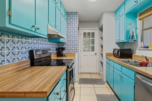 kitchen with stainless steel appliances, under cabinet range hood, a sink, and blue cabinets