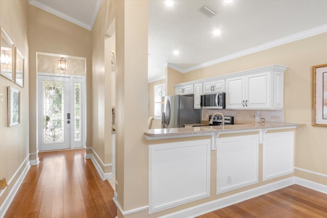 501 Olympic Cir, Saint Augustine, FL 32092 - kitchen featuring appliances with stainless steel finishes, backsplash, light wood finished floors, light stone counters, and white cabinets