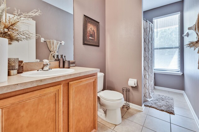 bathroom with tile patterned flooring, vanity, a wealth of natural light, and toilet