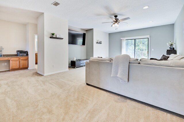 living room with light carpet, a textured ceiling, and ceiling fan