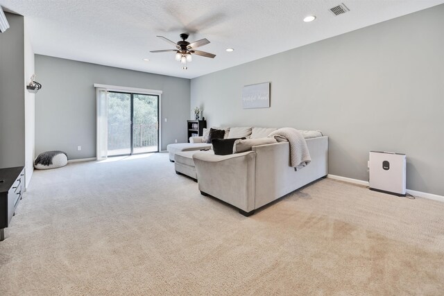 living room featuring light carpet, a textured ceiling, and ceiling fan