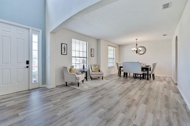 foyer entrance featuring a chandelier, a textured ceiling, and light wood-type flooring