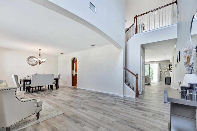 foyer entrance featuring a chandelier, a high ceiling, and light wood-type flooring