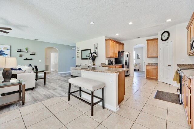 kitchen featuring a breakfast bar, light stone counters, light tile patterned floors, kitchen peninsula, and stainless steel appliances