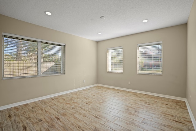 unfurnished room featuring a textured ceiling and light hardwood / wood-style flooring