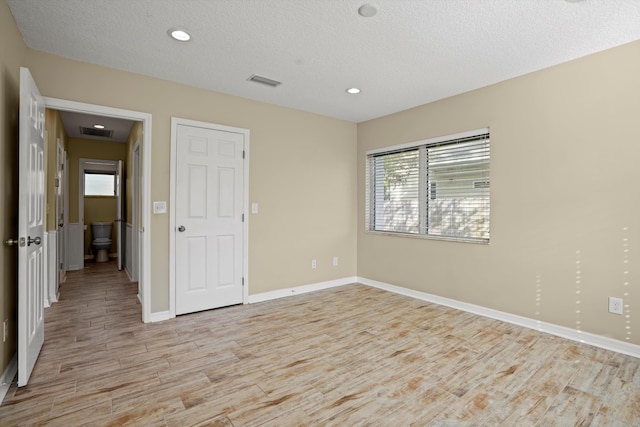 unfurnished room featuring a textured ceiling and light hardwood / wood-style floors