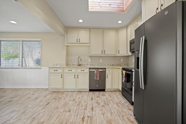 kitchen with cream cabinetry, light wood-type flooring, sink, and appliances with stainless steel finishes