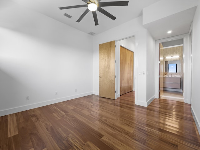 unfurnished bedroom with dark hardwood / wood-style flooring, ensuite bathroom, and ceiling fan