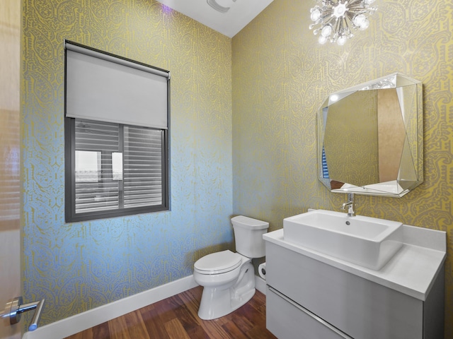 bathroom with wood-type flooring, vanity, toilet, and a notable chandelier