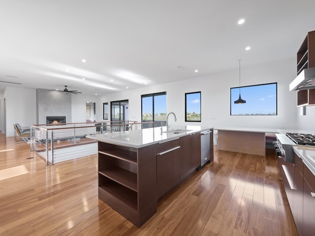 kitchen with sink, hanging light fixtures, stainless steel dishwasher, a spacious island, and dark brown cabinets