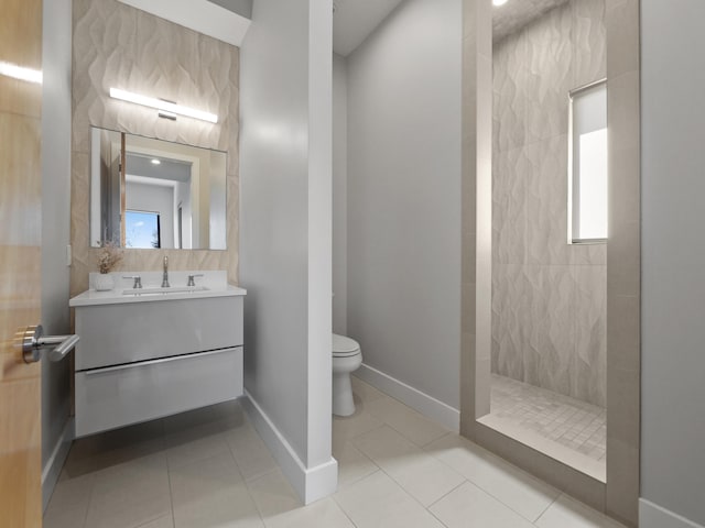 bathroom featuring tile patterned floors, vanity, a tile shower, and toilet