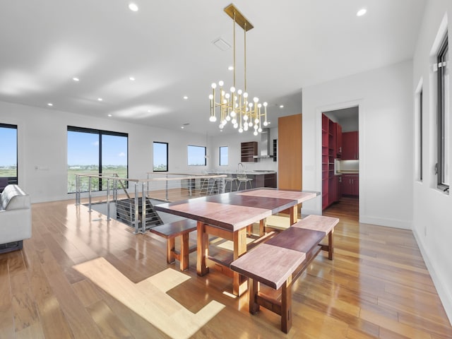 dining space featuring light wood-type flooring and an inviting chandelier