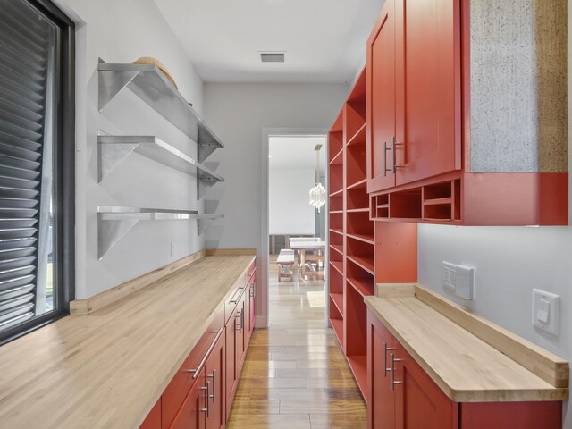 interior space featuring a chandelier, butcher block countertops, light hardwood / wood-style flooring, and hanging light fixtures