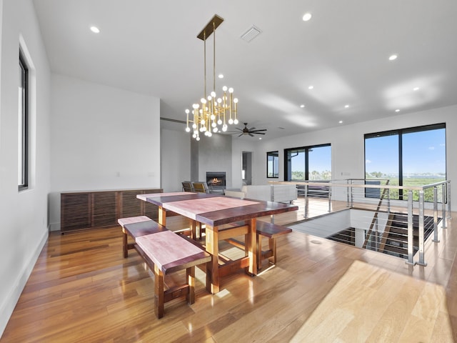 dining area featuring ceiling fan, a fireplace, and light hardwood / wood-style flooring