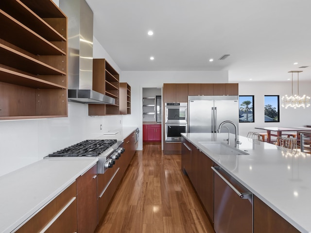 kitchen with sink, wall chimney exhaust hood, hanging light fixtures, dark wood-type flooring, and stainless steel appliances