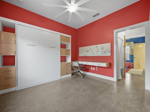 interior space with ceiling fan, built in desk, and concrete floors