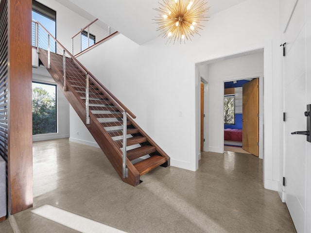 stairway featuring a chandelier and concrete floors