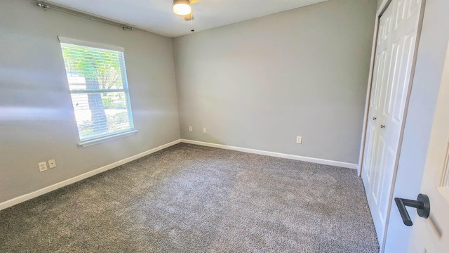 carpeted empty room with baseboards and a ceiling fan